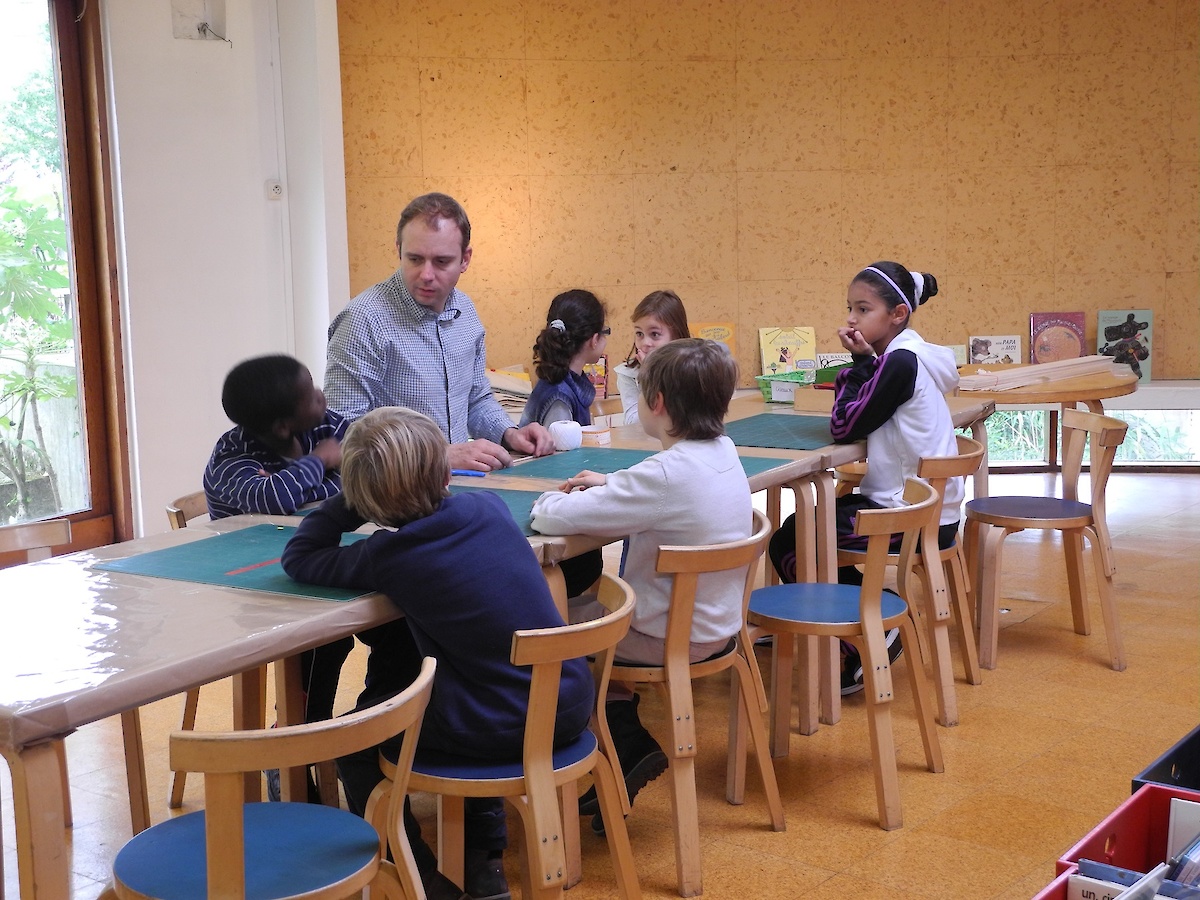 Nicolas Boulard entouré d'enfants autour d'une table de la Petite Bibliothèque Ronde