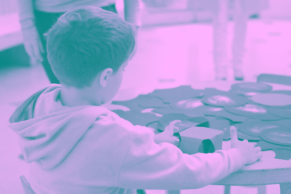 Un enfant joue avec du carton sur une table