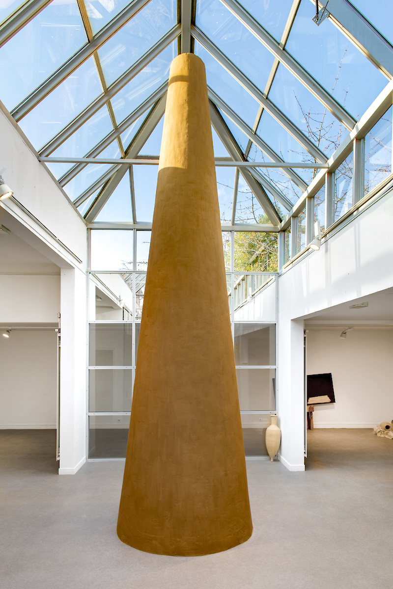 monument en terre en forme de cheminée au milieu d'une verrière