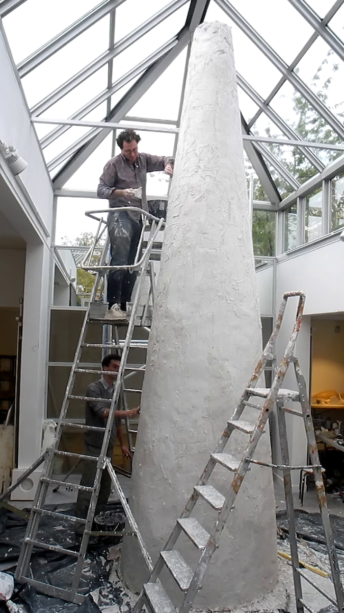 Un homme en haut d'une échelle construit une tour conique blanche