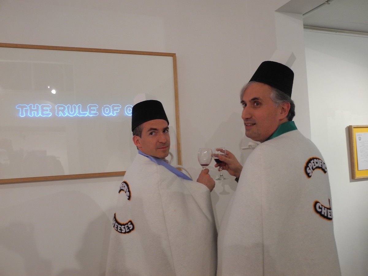 Des personnes en uniforme de la confrérie du fromage avec un verre de vin