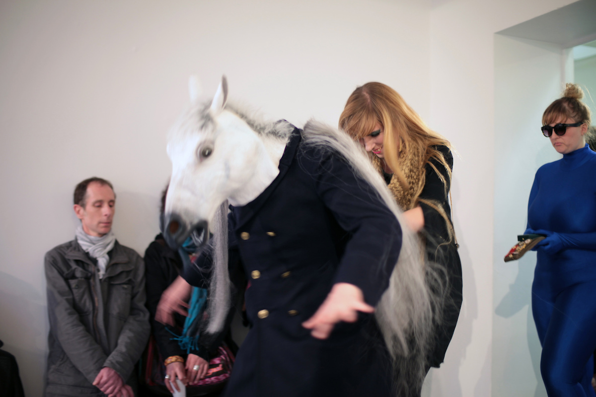 Une femme pousse un comédien avec un masque de cheval