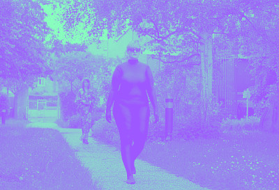 Une femme avec un costume bleu marche dans une allée extérieure
