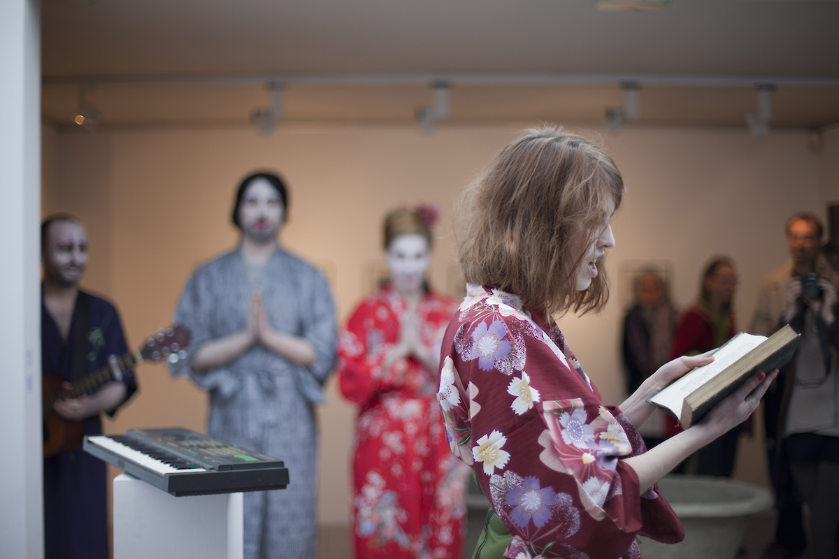 Une femme en kimono de profil semble lire un livre