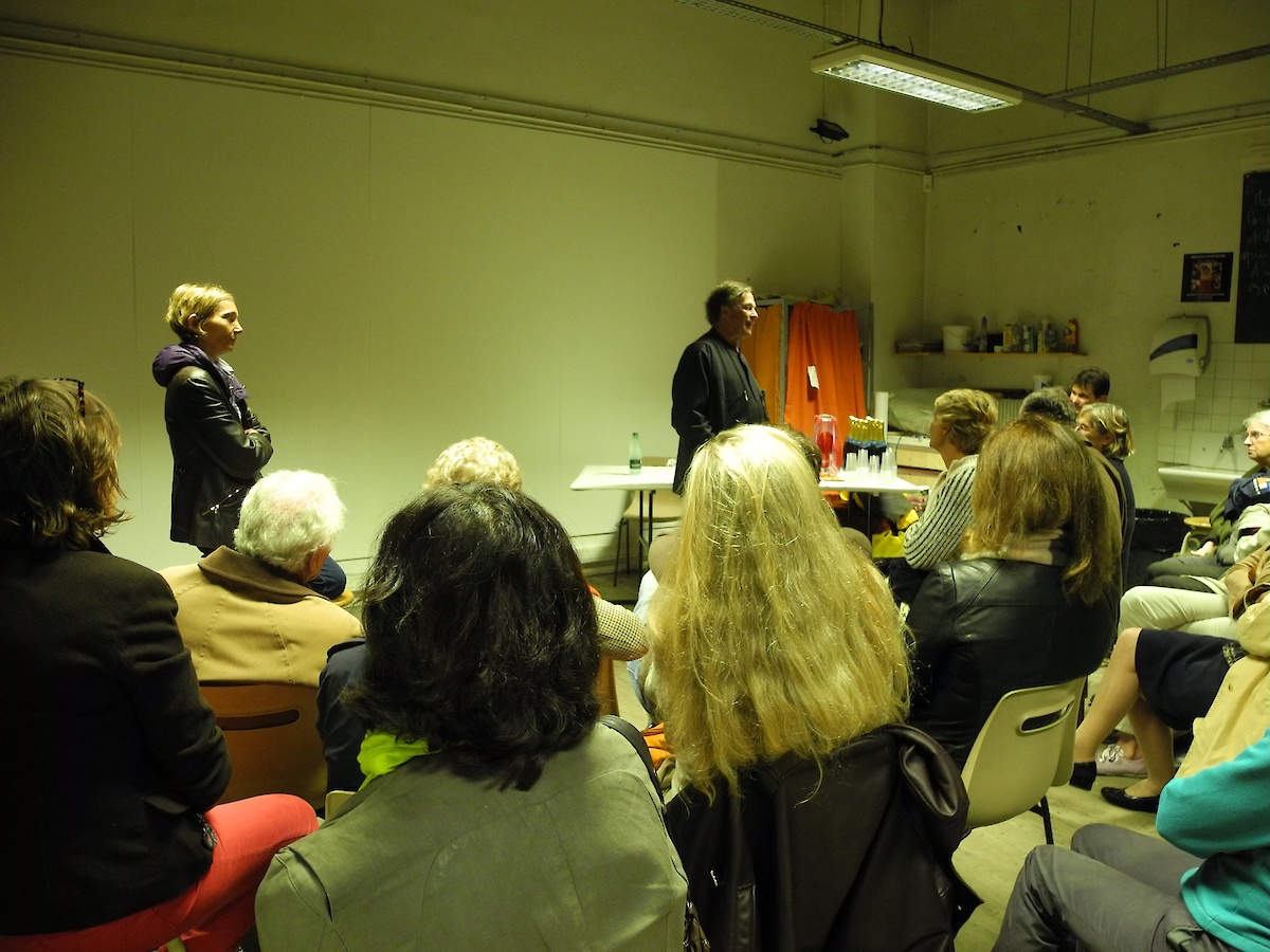 Des personnes assises autour d'une conférence dans un atelier d'artiste