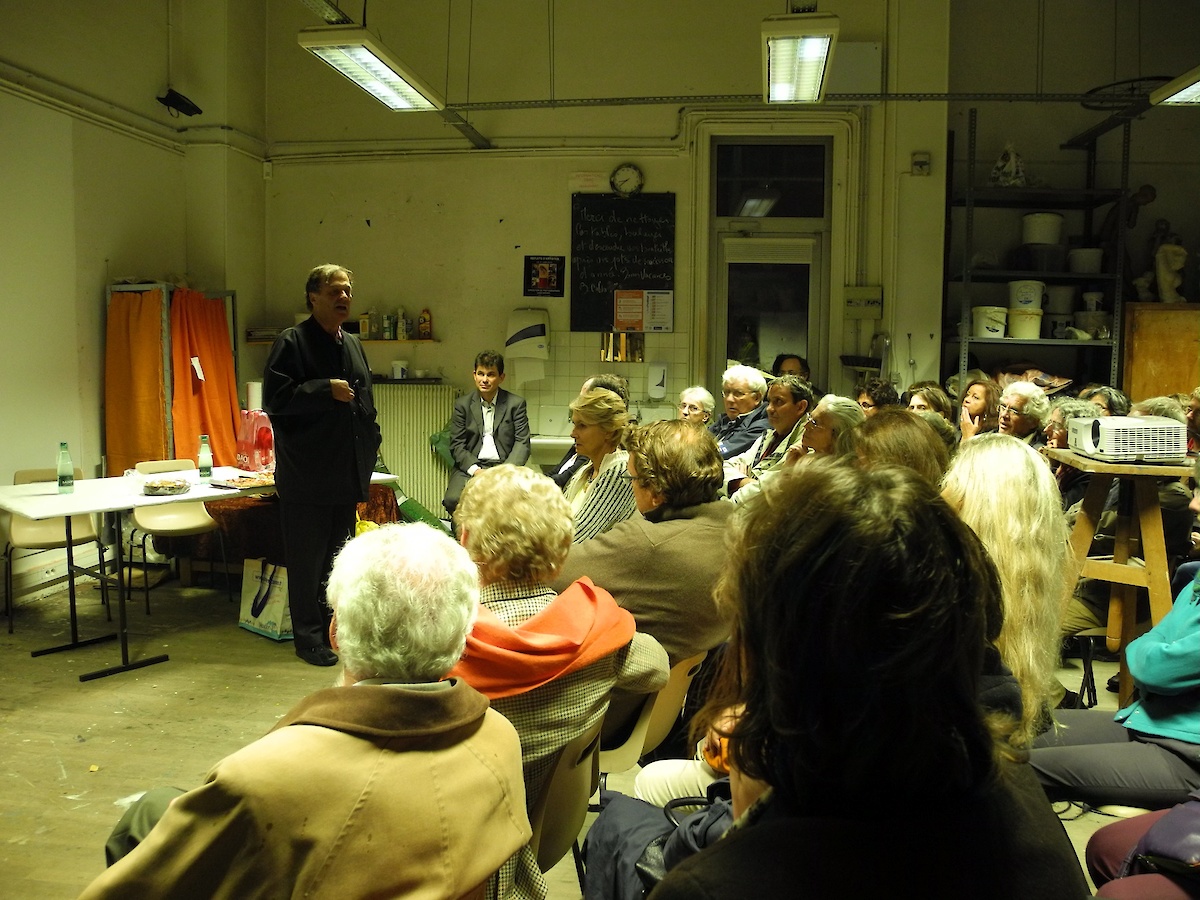 Des personnes assises autour d'un conférencier dans un atelier d'artiste