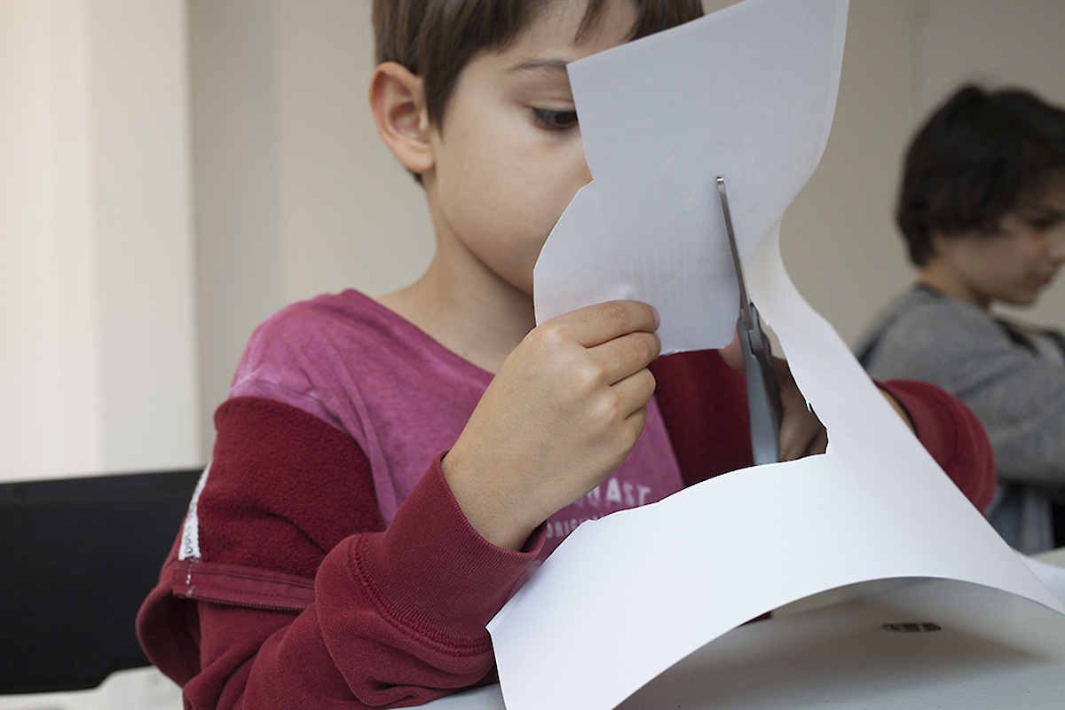 Un enfant découpe une feuille blanche