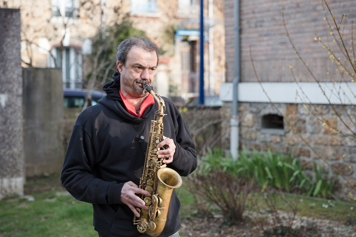 Un homme joue du saxophone dans un jardin