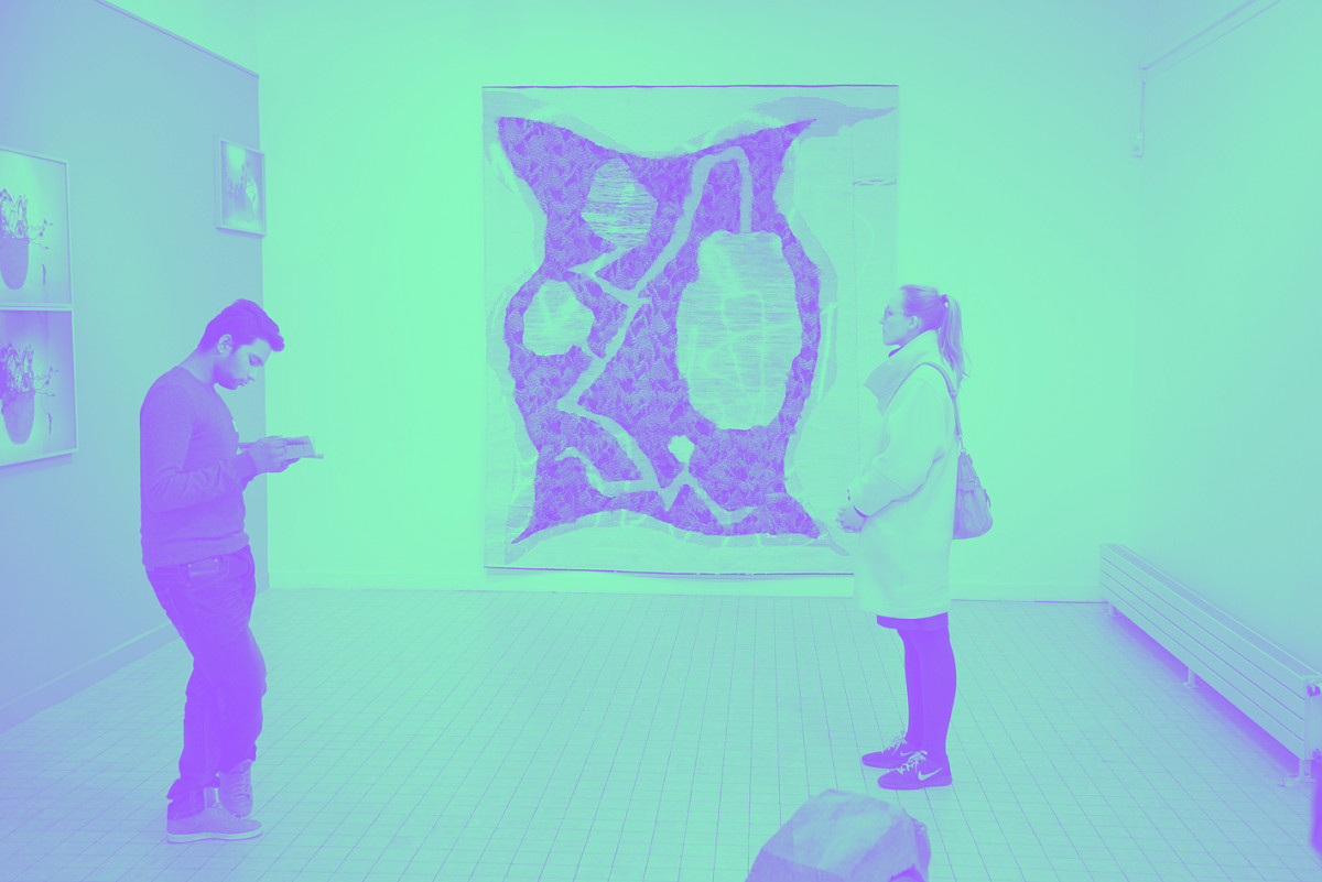 tapisserie accrochée au mur et deux personnes qui regardent les œuvres