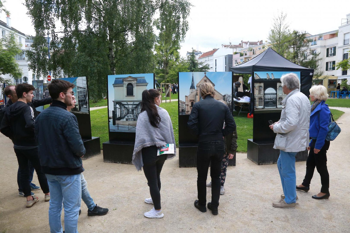 Des personnes sont rassemblées autour de photographies en plein air