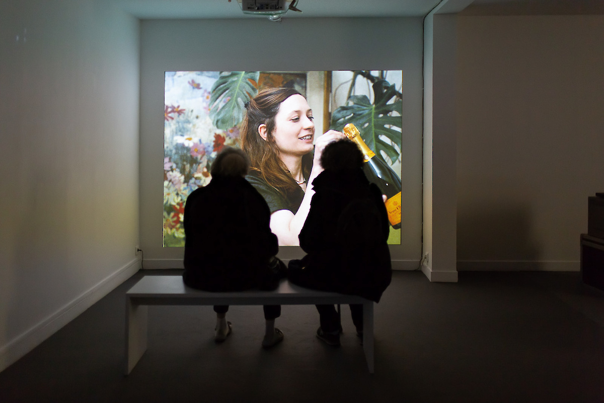 Deux personnes regardent une femme sur écran géant