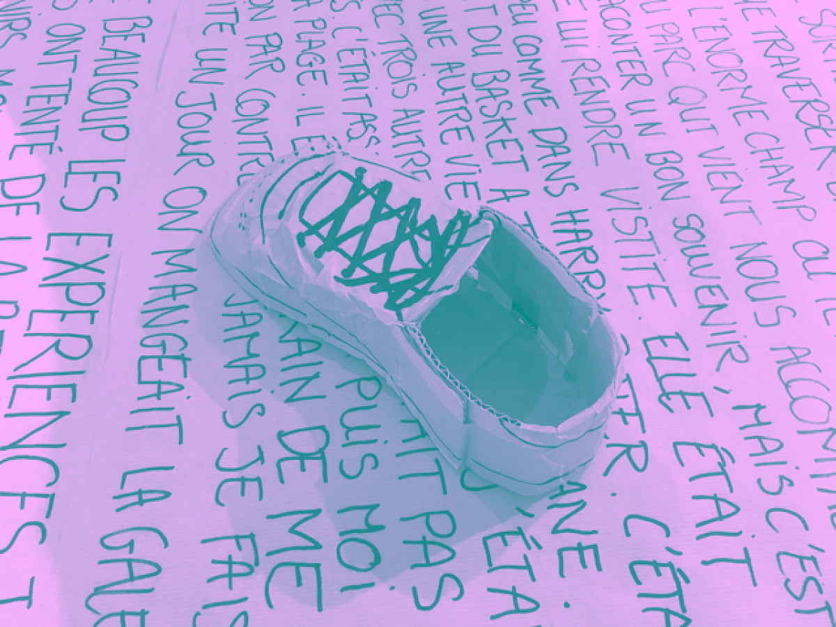 Une chaussure en carton posé sur une plaque de carton sur laquelle un texte est écrit
