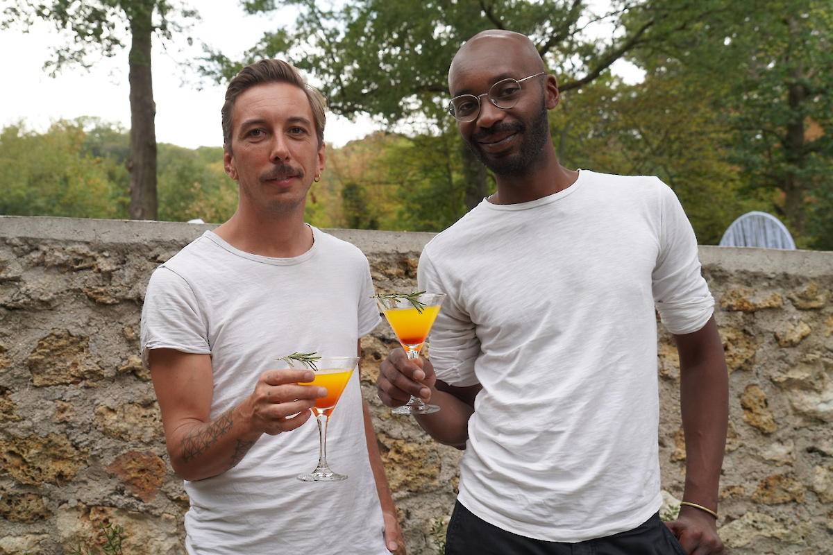 2 personnes trinquent avec un verre de boisson orangée