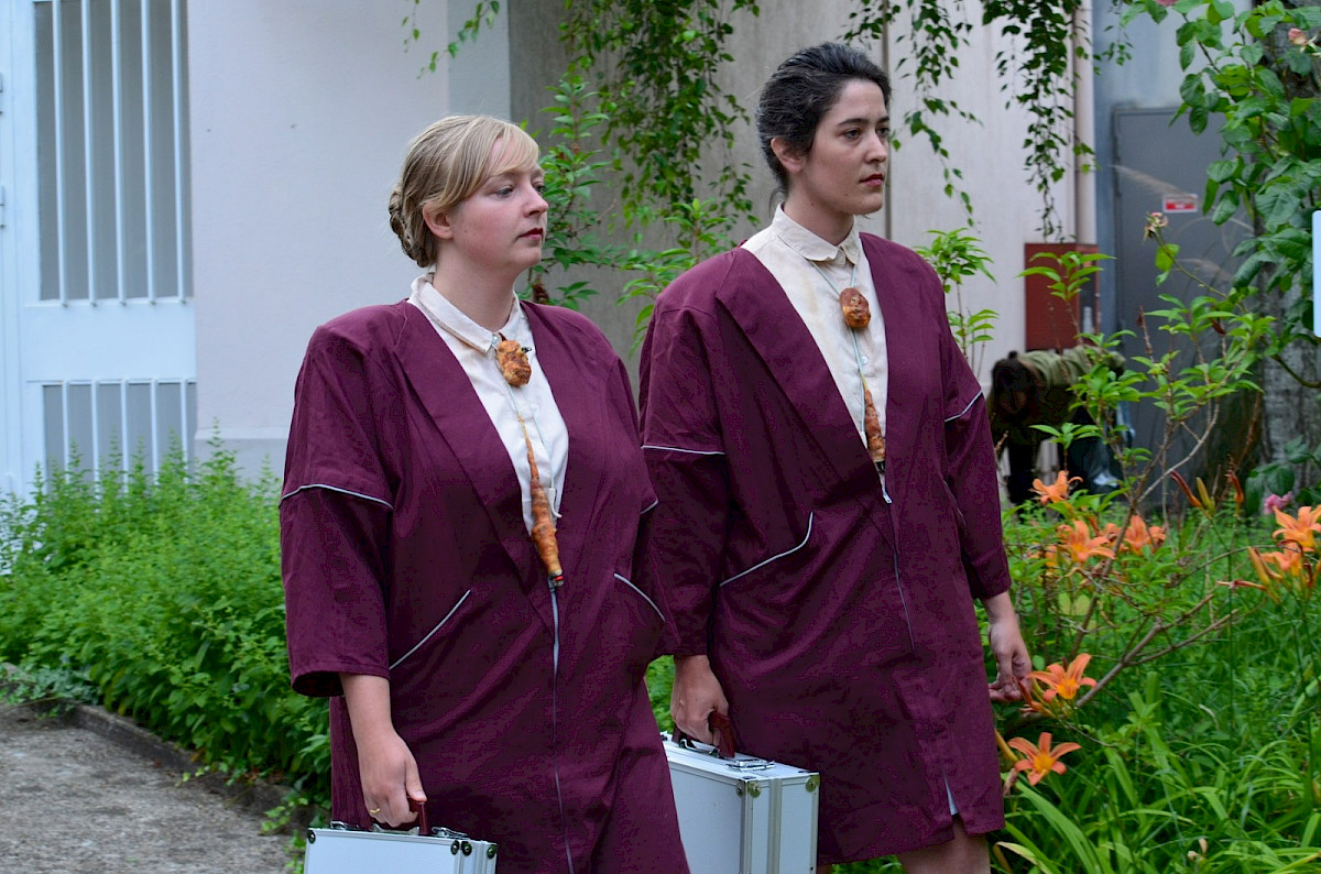 deux femmes en uniforme portent une mallette et un collier de carottes